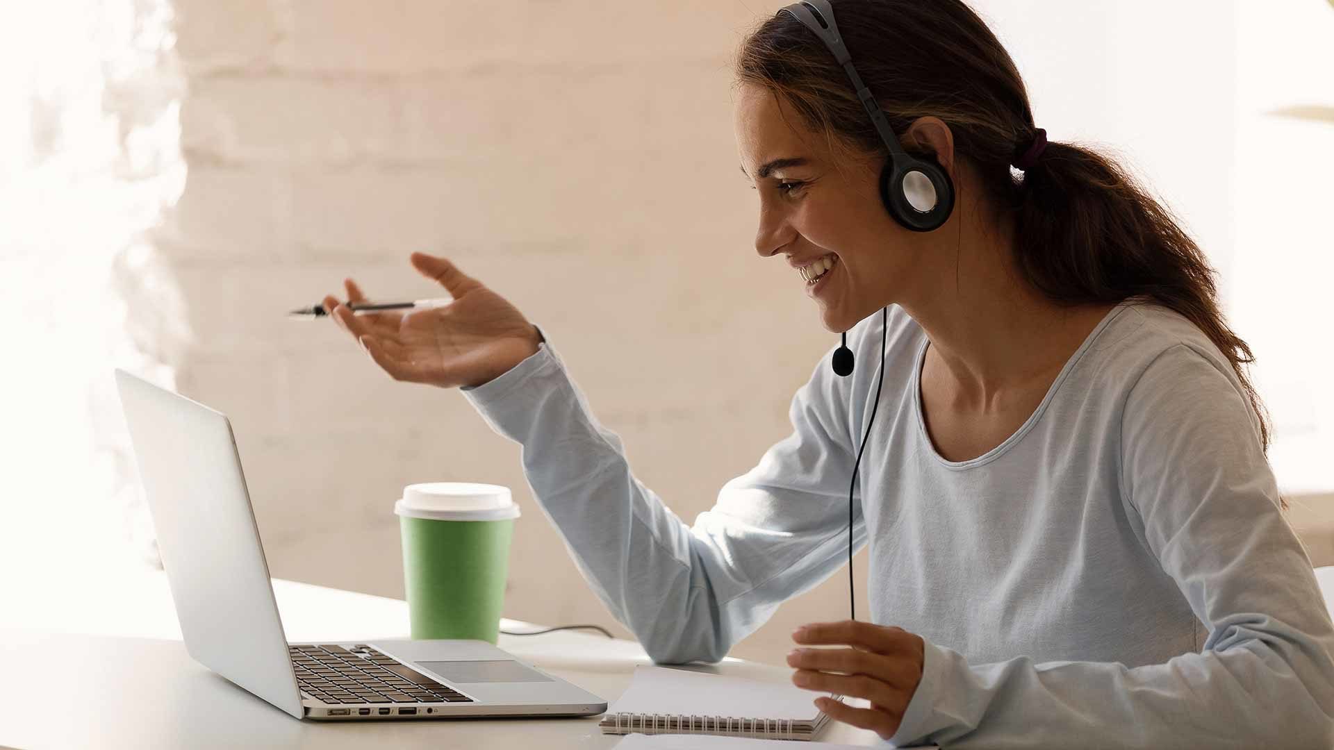 Lachende Customer Service Agentin mit Headset vor einem Laptop
